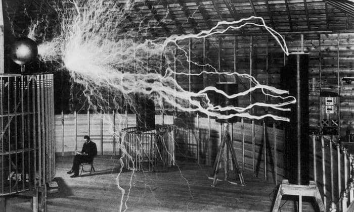 Nikola Tesla reading by the light of a Tesla coil.
